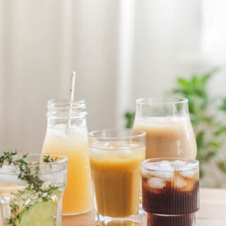 Various refreshing non-alcoholic drinks in glasses with ice. Fruit juice, lemonades, iced coffee, smoothies on wood table. Copy space. Front view